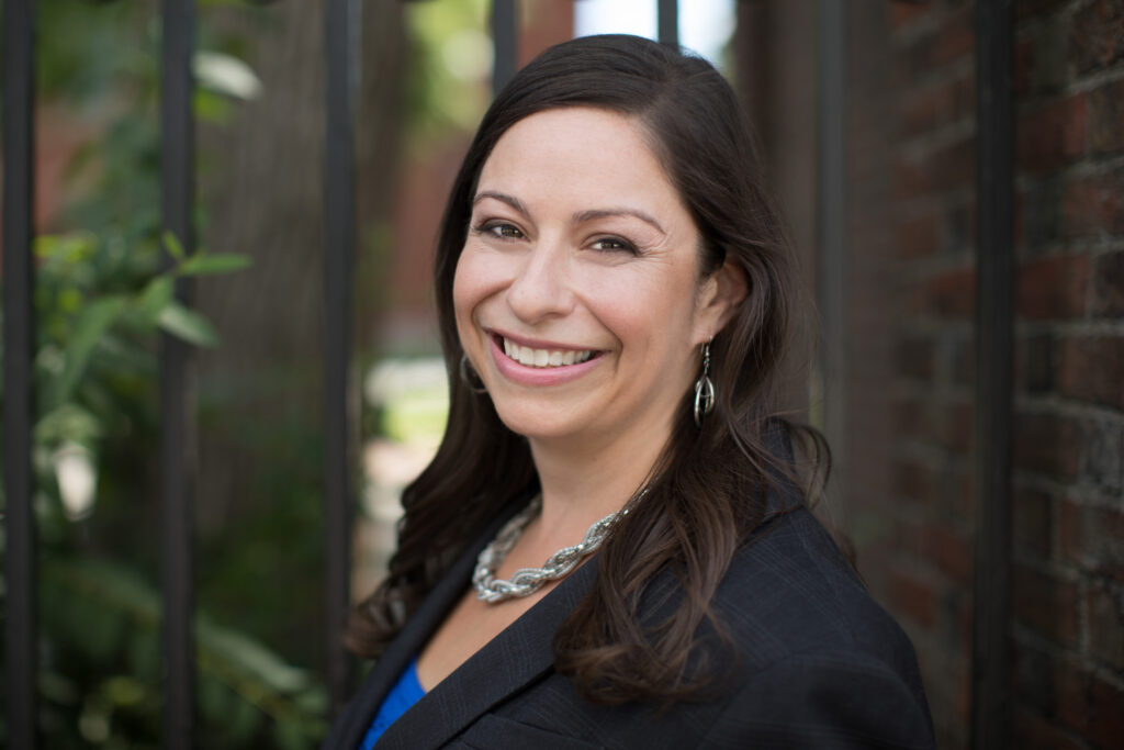 a woman in a black jacket smiling for the camera