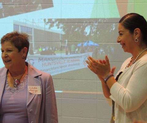 two women standing in front of a projector screen